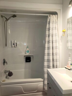 Une salle de bain équipée d’une baignoire, d’une douche et d’un meuble-lavabo avec un miroir.