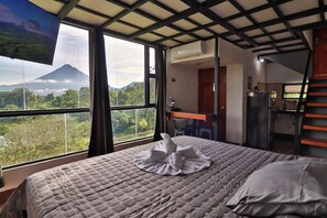 Une chambre avec un lit, un bureau et une vue sur la montagne.