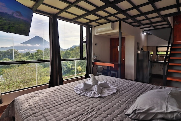 Een slaapkamer met een bed, een bureau en uitzicht op een berg.