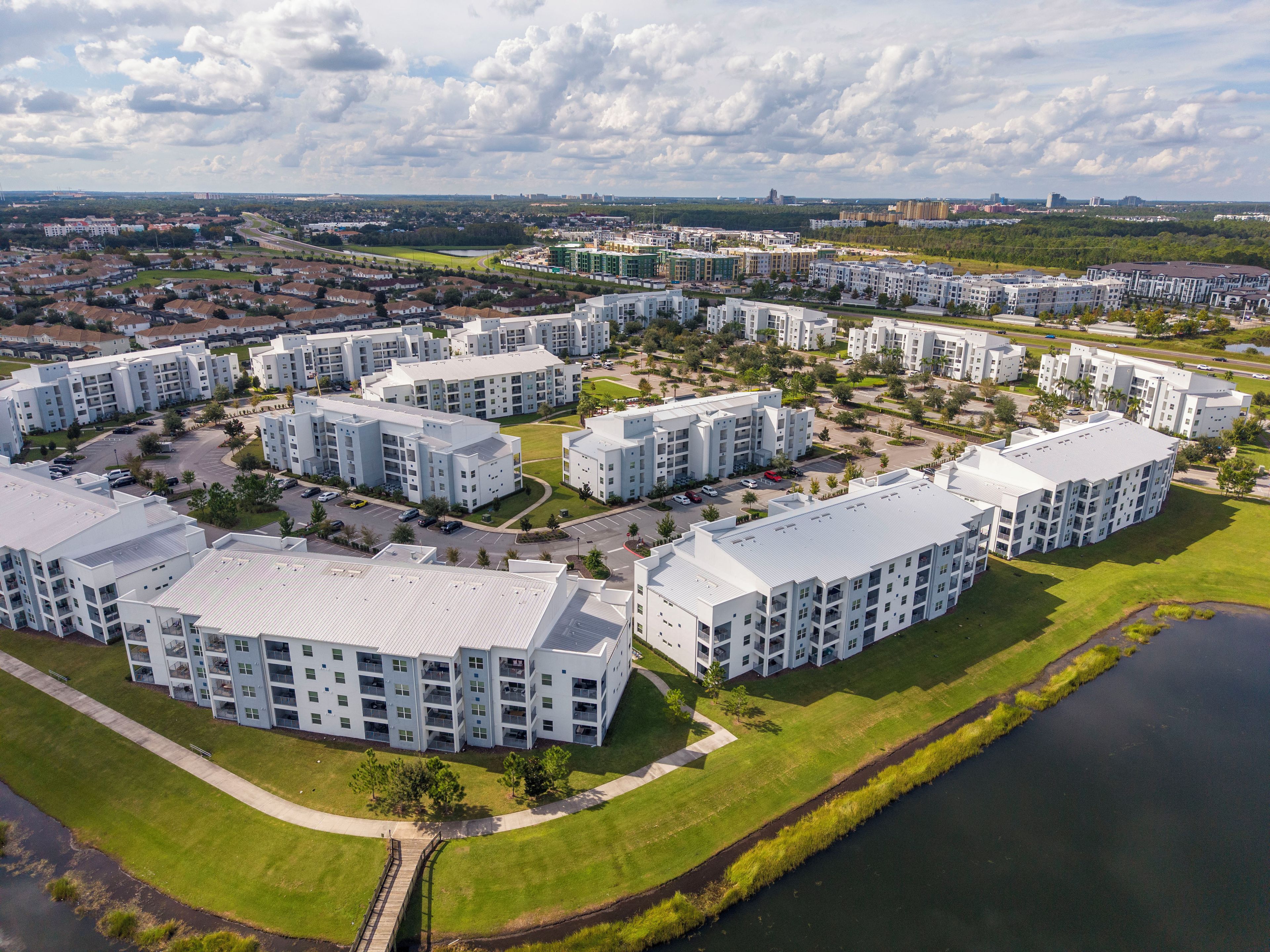 A residential complex with multiple apartment buildings, a central green space, and a body of water.