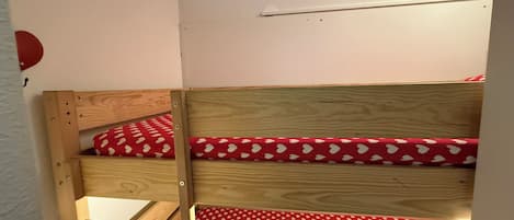 Un lit superposé avec une couvre-lit à pois rouges et une tête de lit en bois.