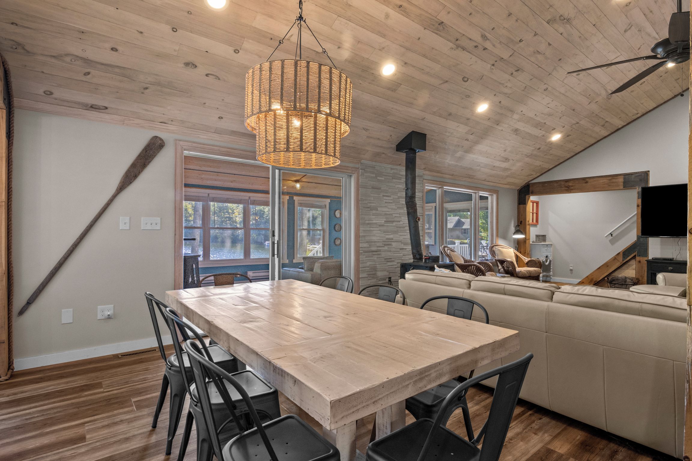 A spacious kitchen with a wooden table, chairs, and a hanging light fixture.