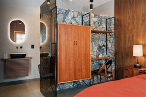 A modern bathroom with a stone wall, wooden cabinets, a sink, and a mirror.