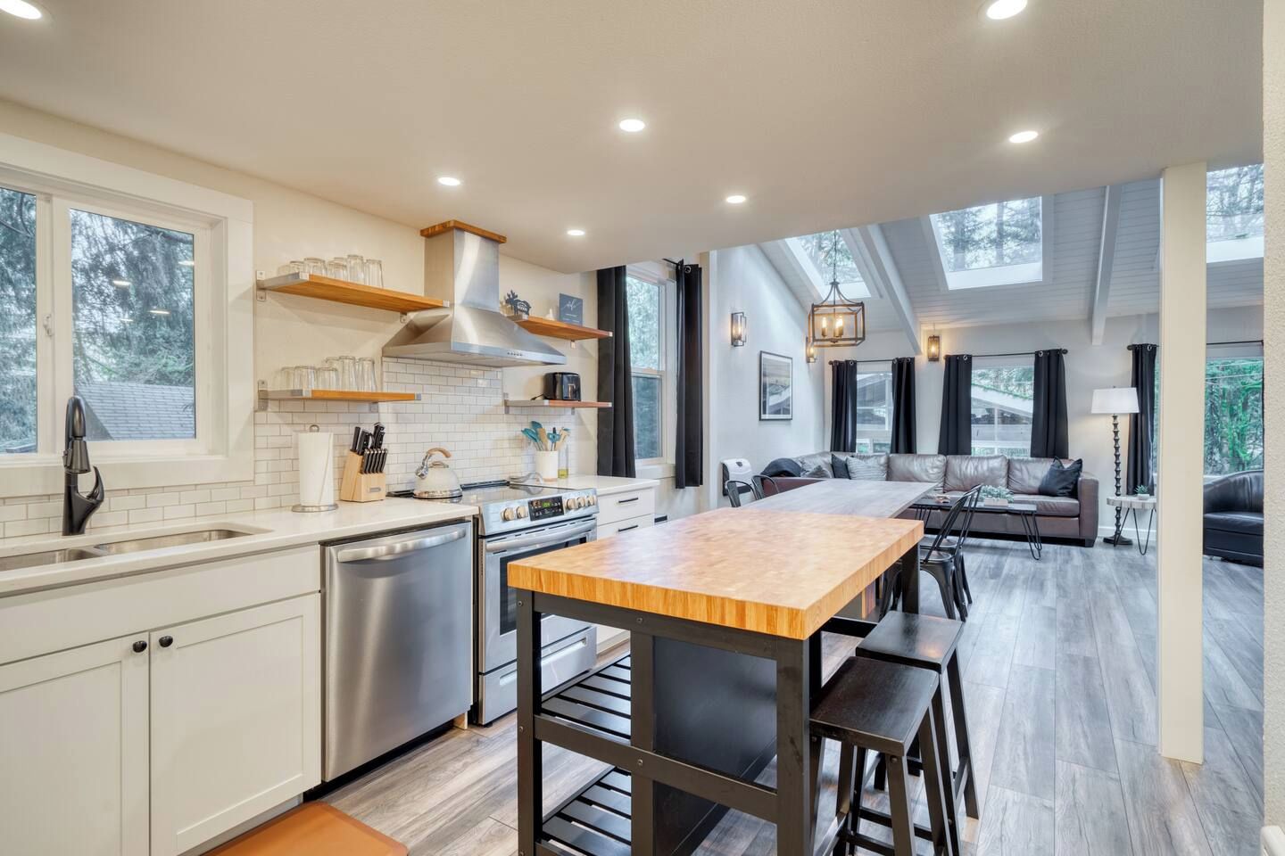 A modern kitchen with a central island, stainless steel appliances, and a dining area with a sofa and chairs.