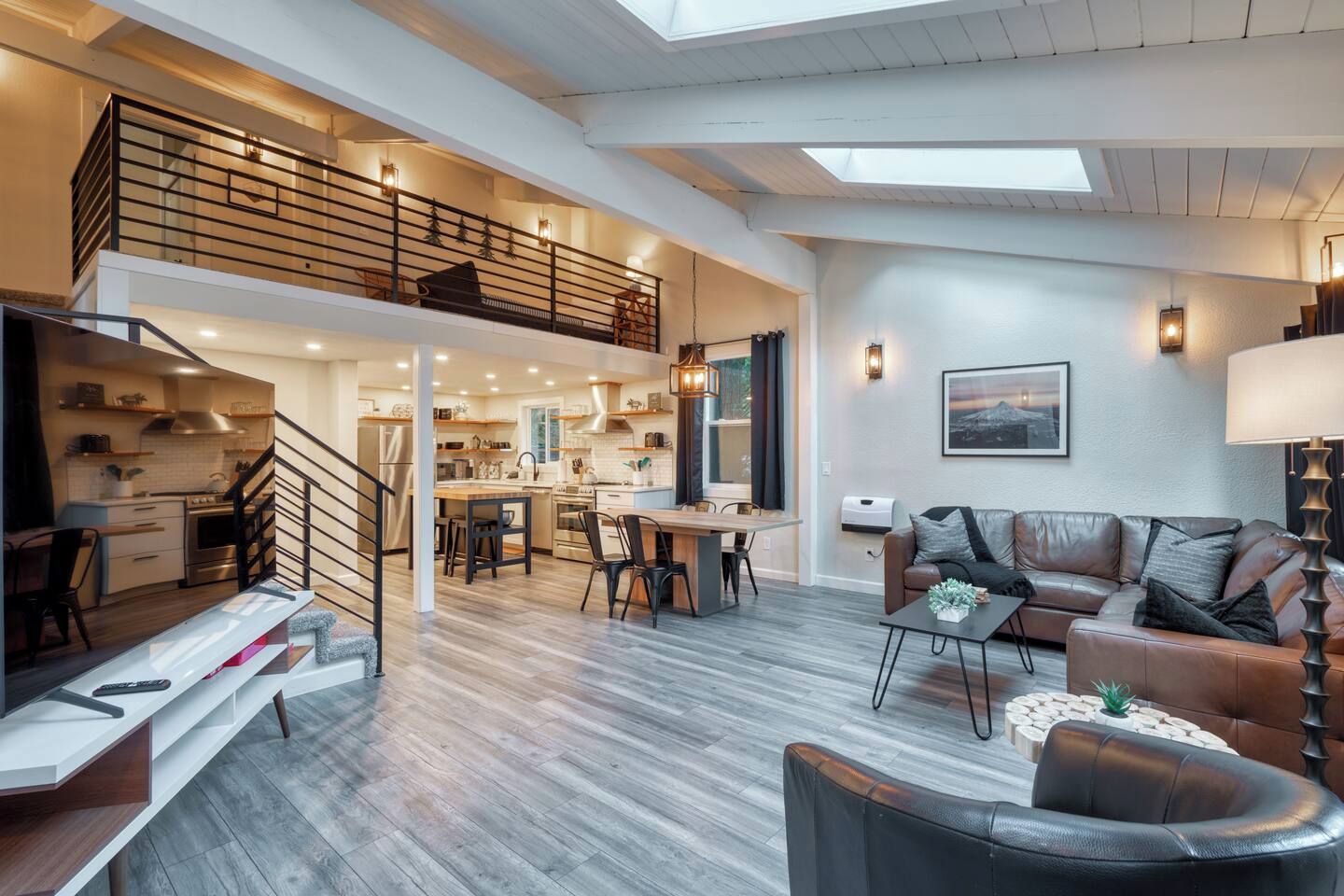 Amplo apartamento estilo loft com mezanino, cozinha, sala de jantar e sala de estar com sofá e mesa de centro.