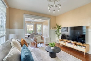 Un salon comprenant un canapé, une table basse, un téléviseur et un coin repas avec des chaises et une table.