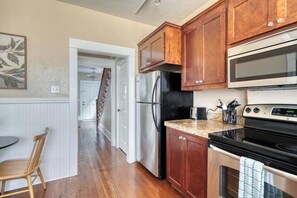 A kitchen with wooden cabinets, a stainless steel refrigerator, a microwave, and a stove. - Your Front Door Opens onto Mississippi Ave (Portland)