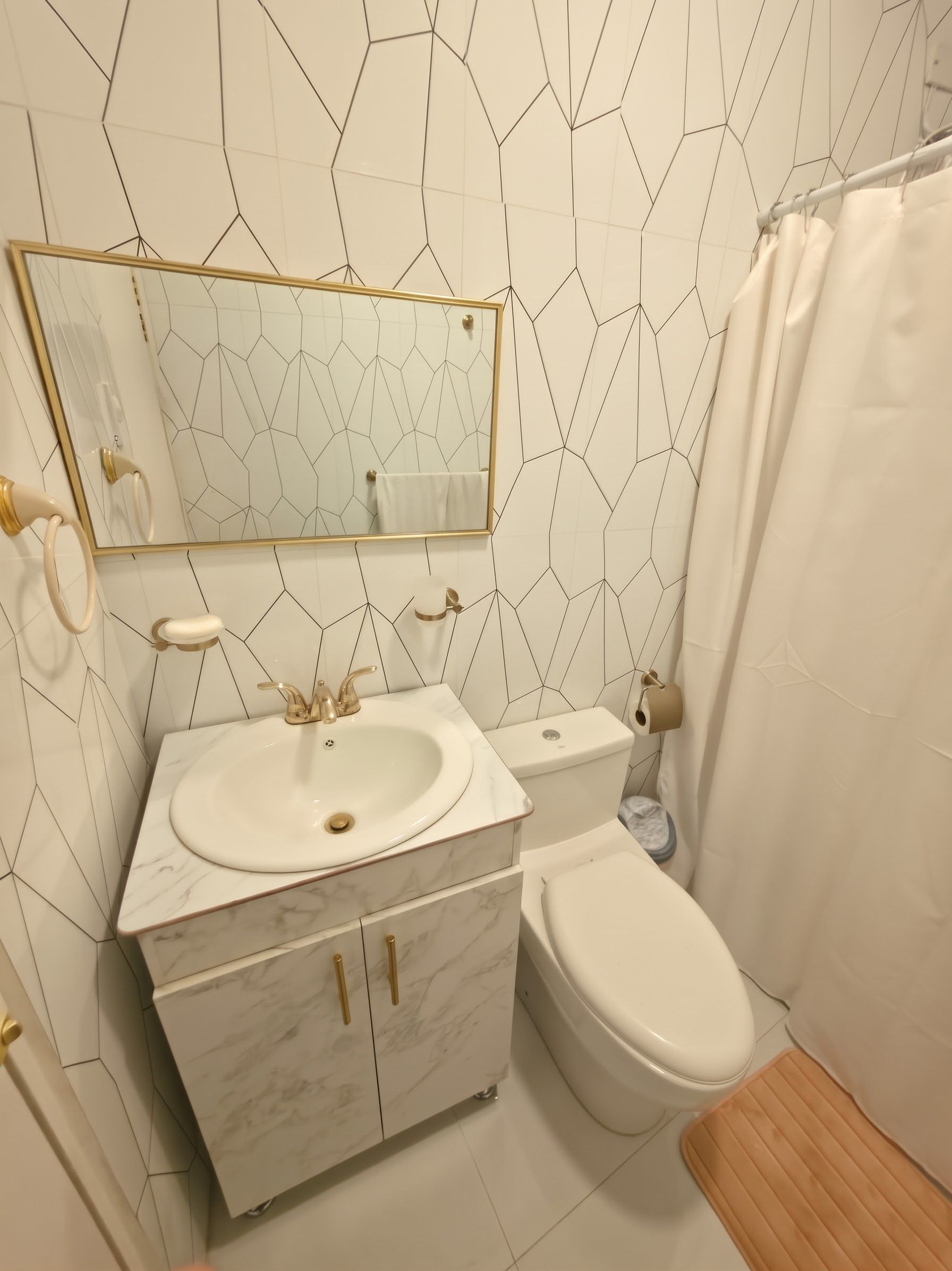 Un baño con lavamanos de mármol, inodoro y cortina de ducha.