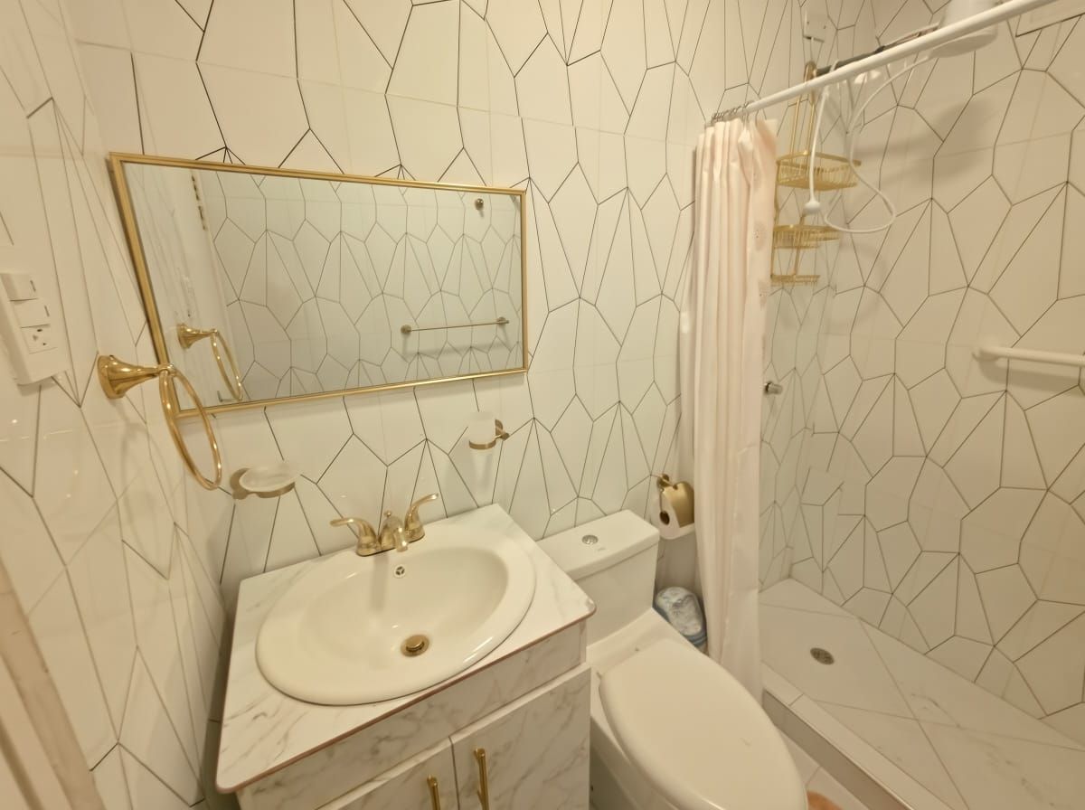 Un baño con lavamanos blanco, inodoro y zona de ducha.
