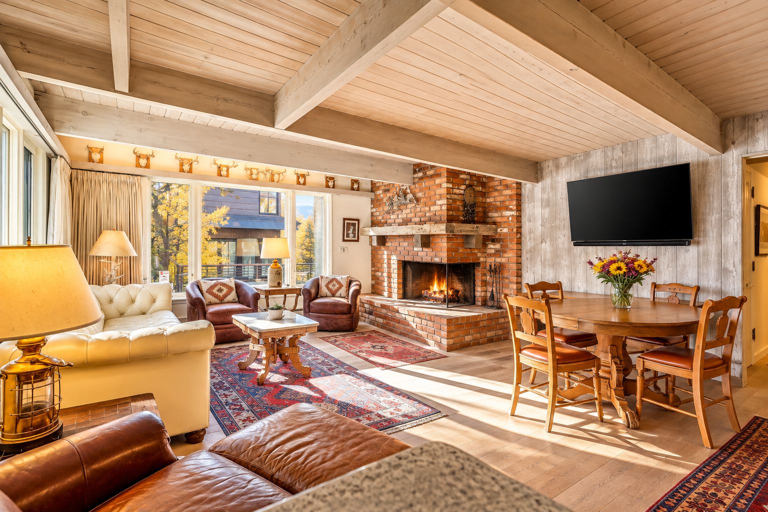 Una sala de estar acogedora con chimenea, sofás de cuero, una mesa de comedor y un televisor montado en la pared.