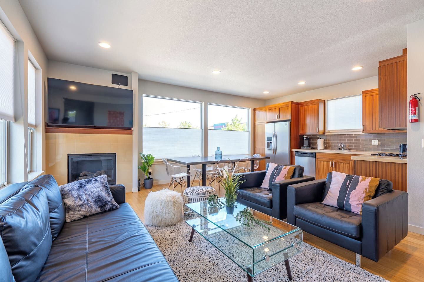 A modern living room with a fireplace, leather sofas, a glass coffee table, and a view of the outside.