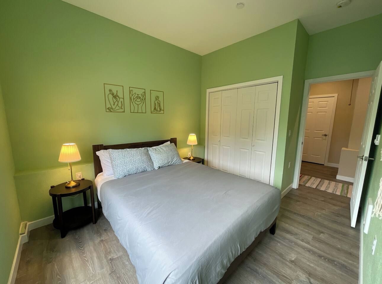 Une chambre à coucher comprenant un lit, deux tables de chevet, une commode, une armoire et une porte donnant sur une autre pièce.