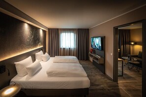 Ein Hotelzimmer mit einem großen Bett, einem Fernseher, einem Schreibtisch und einem Spiegel.