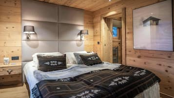 Una habitación acogedora de madera con una cama, dos lámparas de pared y un cuadro grande con marco.
