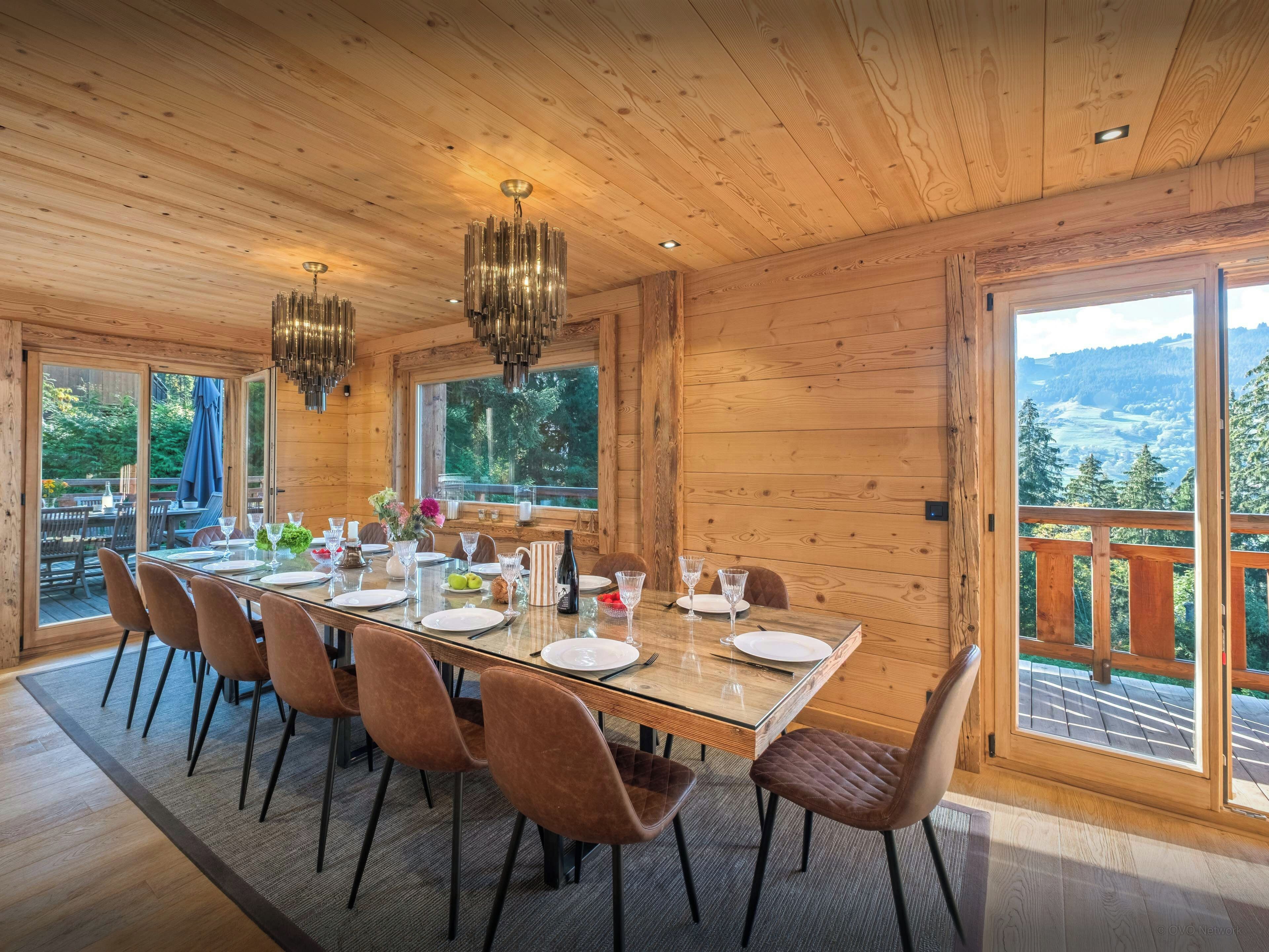 Comedor con paneles de madera, una mesa de cristal, sillas y una araña.