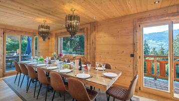 Comedor con paneles de madera, una mesa de cristal, sillas y una araña.