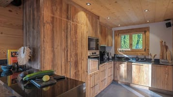 Une cuisine moderne avec des meubles en bois, un plan de travail noir et une fenêtre qui laisse entrer la lumière naturelle.