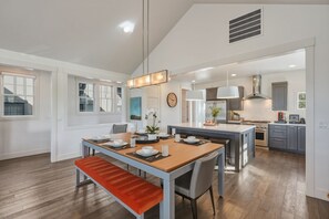 A spacious kitchen with modern appliances, a dining area with a bench, and a large island. - Tetherow Luxe ~ Golf Views ~ Hot Tub ~ Pool Table (Bend)