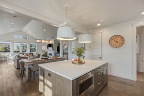 A modern kitchen with a large island, pendant lighting, and a wall clock. - Tetherow Luxe ~ Golf Views ~ Hot Tub ~ Pool Table (Bend)