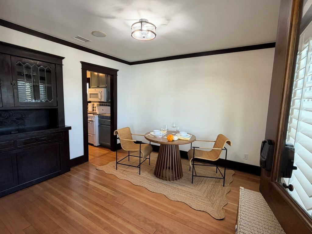A dining area with a round table, four chairs, and a rug.