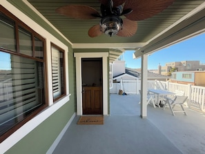 A covered porch with a ceiling fan, a door leading to the interior, and a view of the neighborhood. - The Surfperch Cottage, Private Garage and Patio (Hermosa Beach)