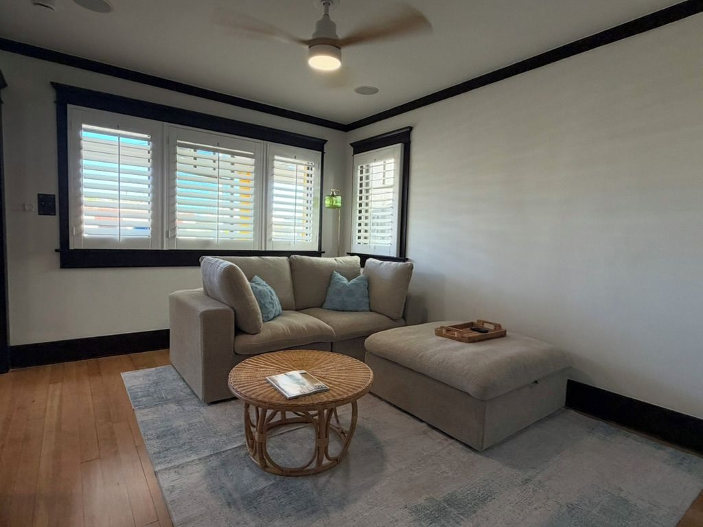 A living room with a sectional sofa, a round coffee table, and a ceiling fan.