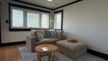 A living room with a sectional sofa, a round coffee table, and a ceiling fan.