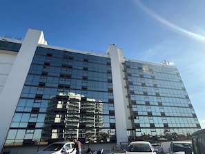 Een modern gebouw met een reflecterende glazen gevel, meerdere verdiepingen en een heldere lucht.