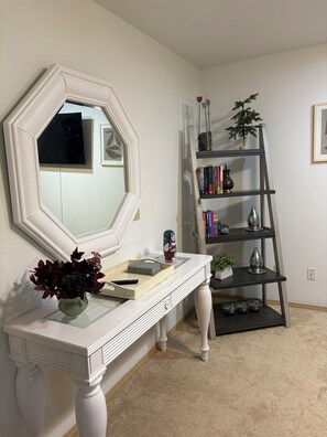 Une pièce comprenant une console blanche, un grand miroir, une bibliothèque et une échelle.
