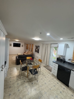 Un espace de vie compact comprenant un coin repas, une kitchenette et un canapé à l’arrière-plan.