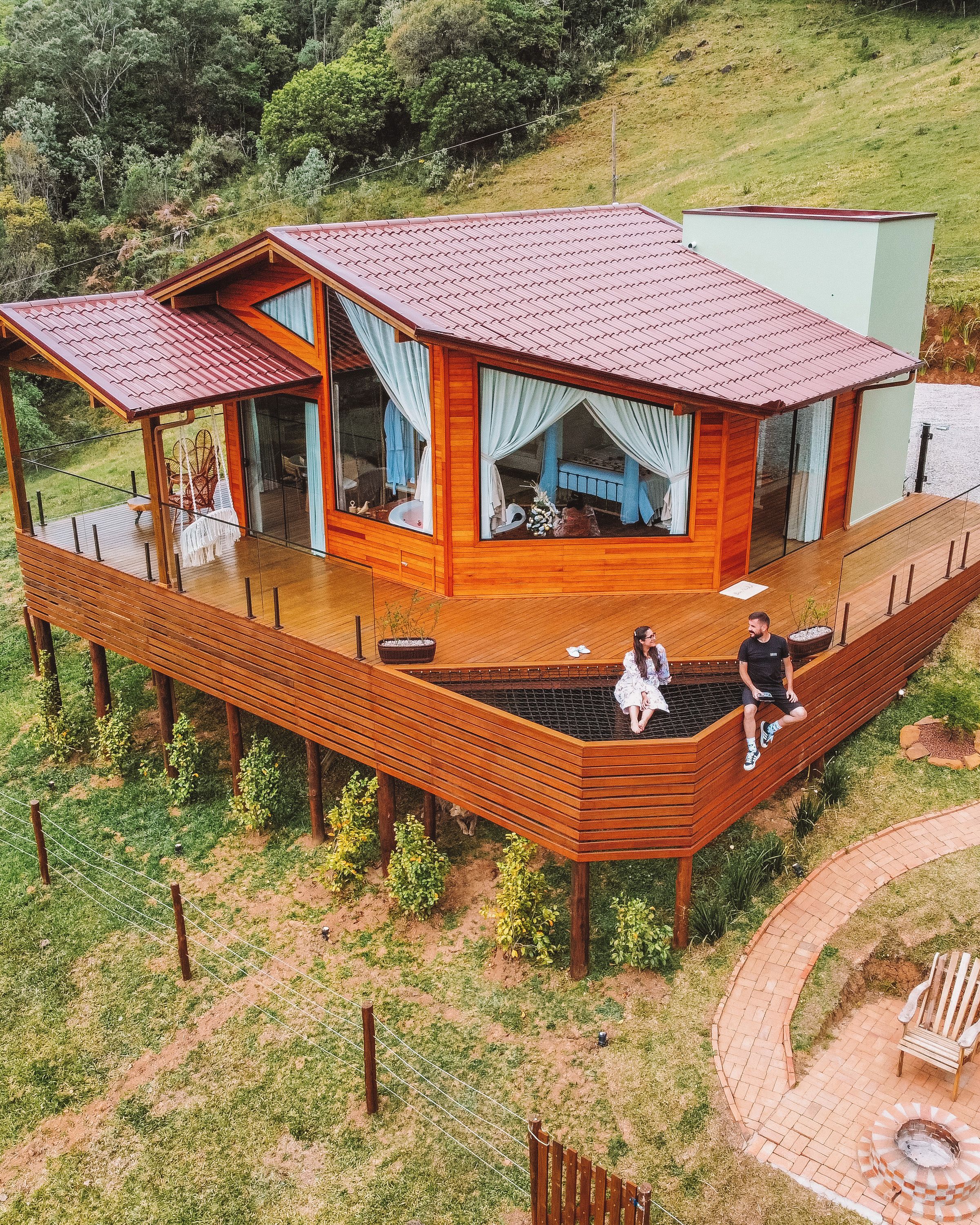 Una casa de madera con techo rojo, una terraza y una chimenea.