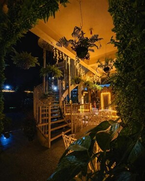 A nighttime outdoor area with a staircase, seating, and potted plants.