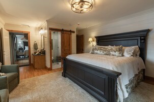 Un dormitorio con una cama grande, una mesita de noche de madera, un espejo, una puerta corredera y una araña.