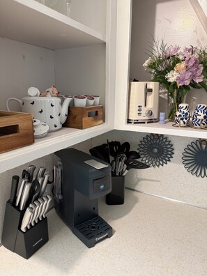 A kitchen counter with a coffee maker, utensils, and decorative items. - Spritely Cottage Near Downtown Springfield (Springfield)
