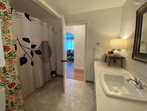 Ett badrum med ett vitt handfat, en spegel och ett duschdraperi med blommönster.