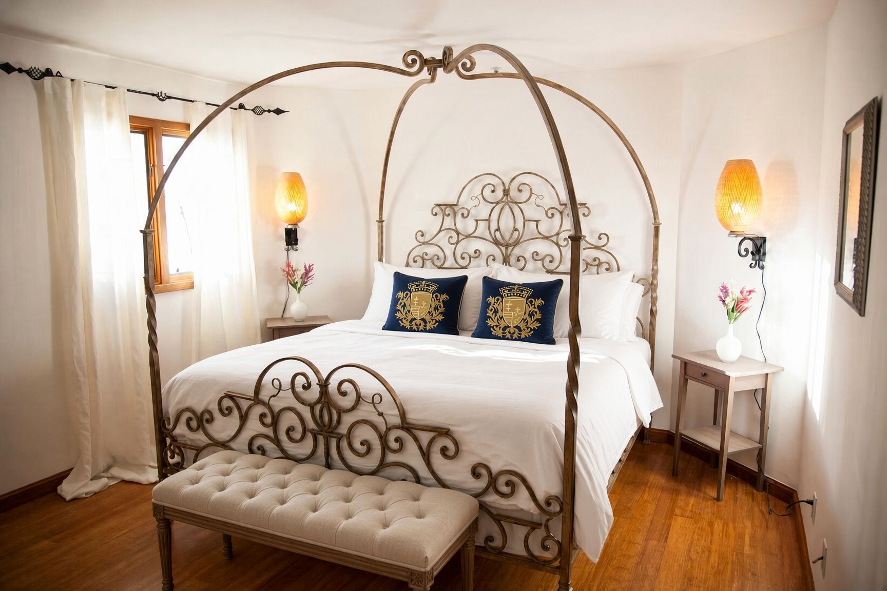 Een kamer met een hemelbed, een nachtkastje met lamp en een bankje.
