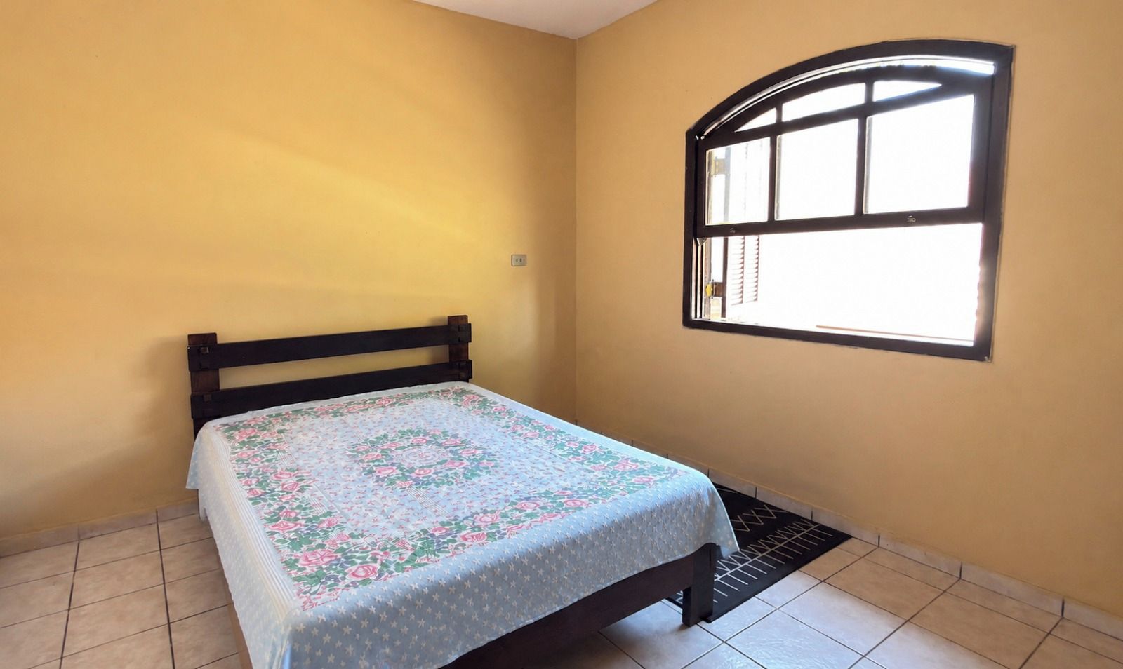 A room with a bed, a window, and a tiled floor.