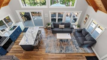 A spacious living area with a kitchen, dining area, and a view of the outdoors through large windows.