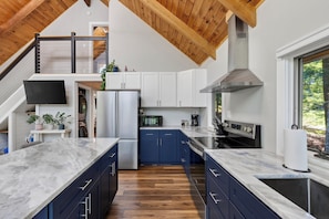 A modern kitchen with marble countertops, stainless steel appliances, and a wooden ceiling. - 3-bed Maine Lakefront Home w/Private Dock & Fire Pit (Waterboro)