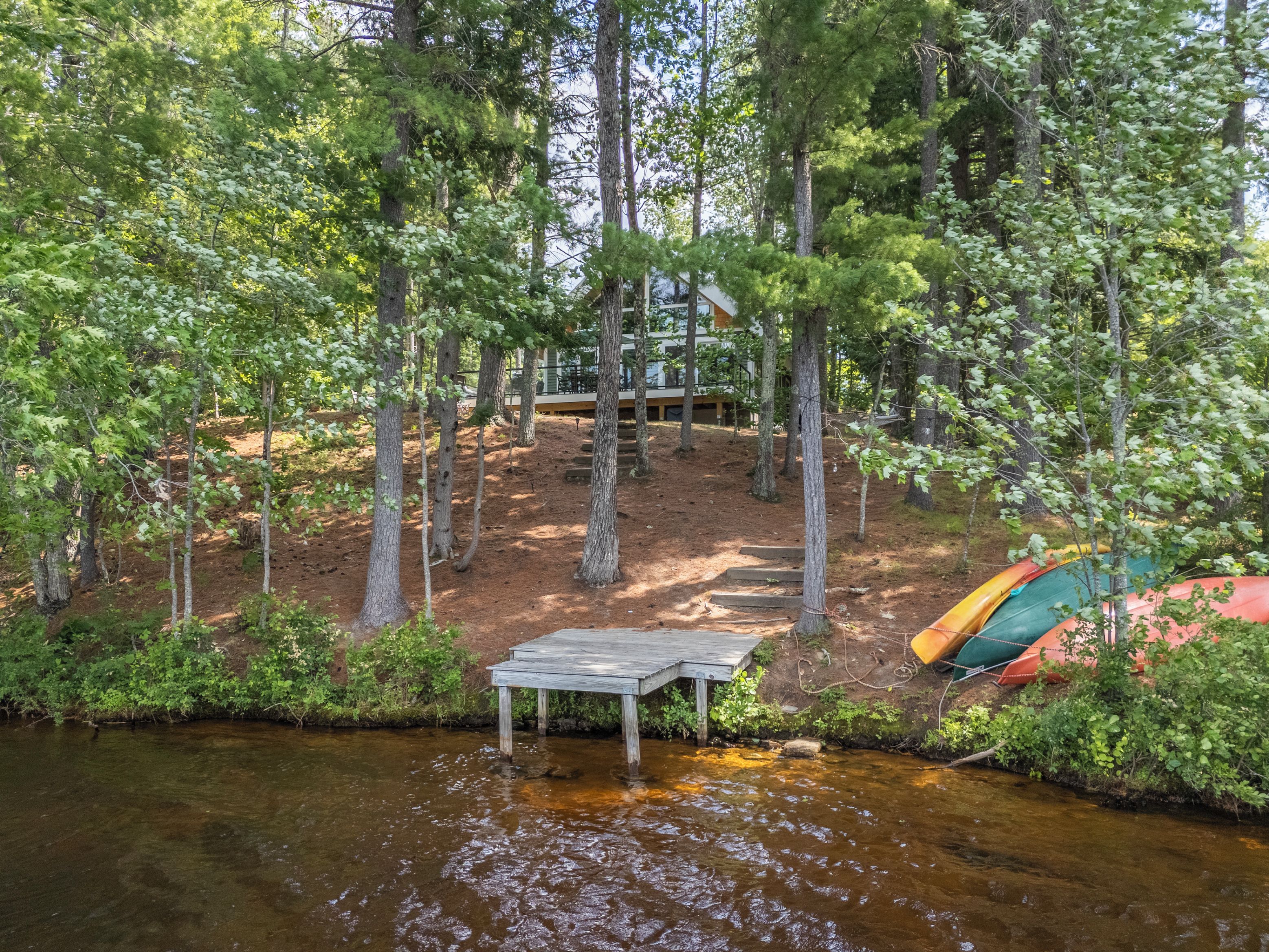 A riverside campsite with a wooden table and a canoe.