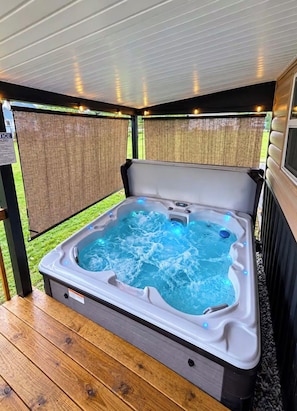 Un jacuzzi con terraza de madera y zona cubierta con techo.