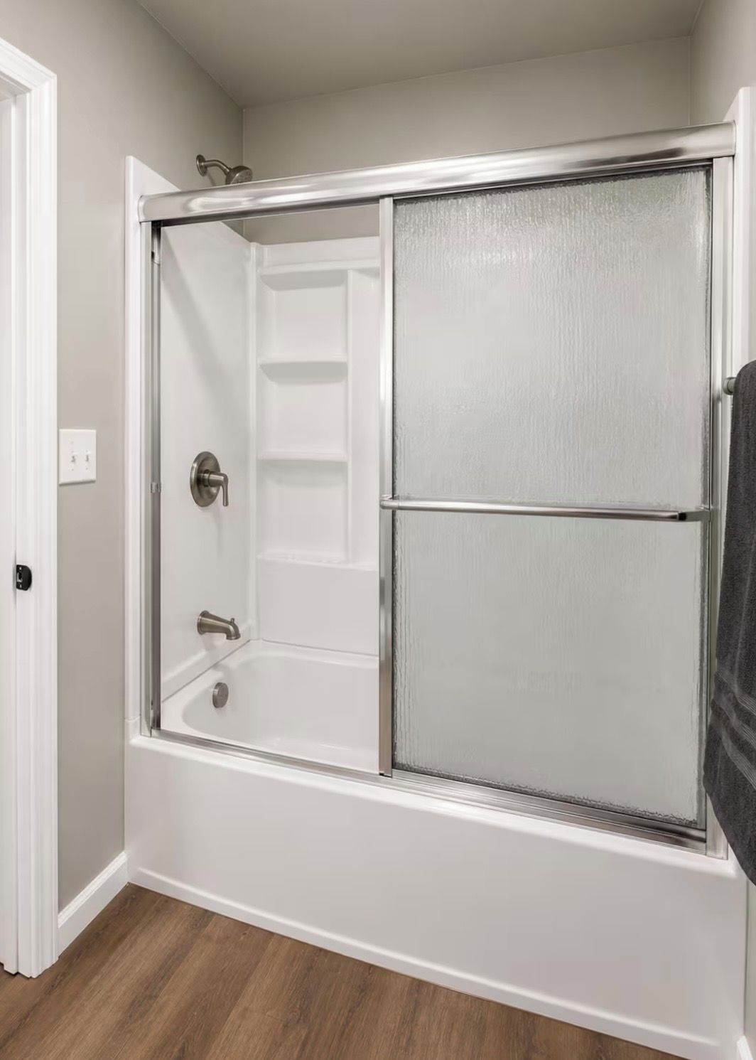 A walk-in shower with a glass door, a built-in shelf, and a shower control panel.
