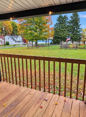 A wooden deck with a view of a park and houses.