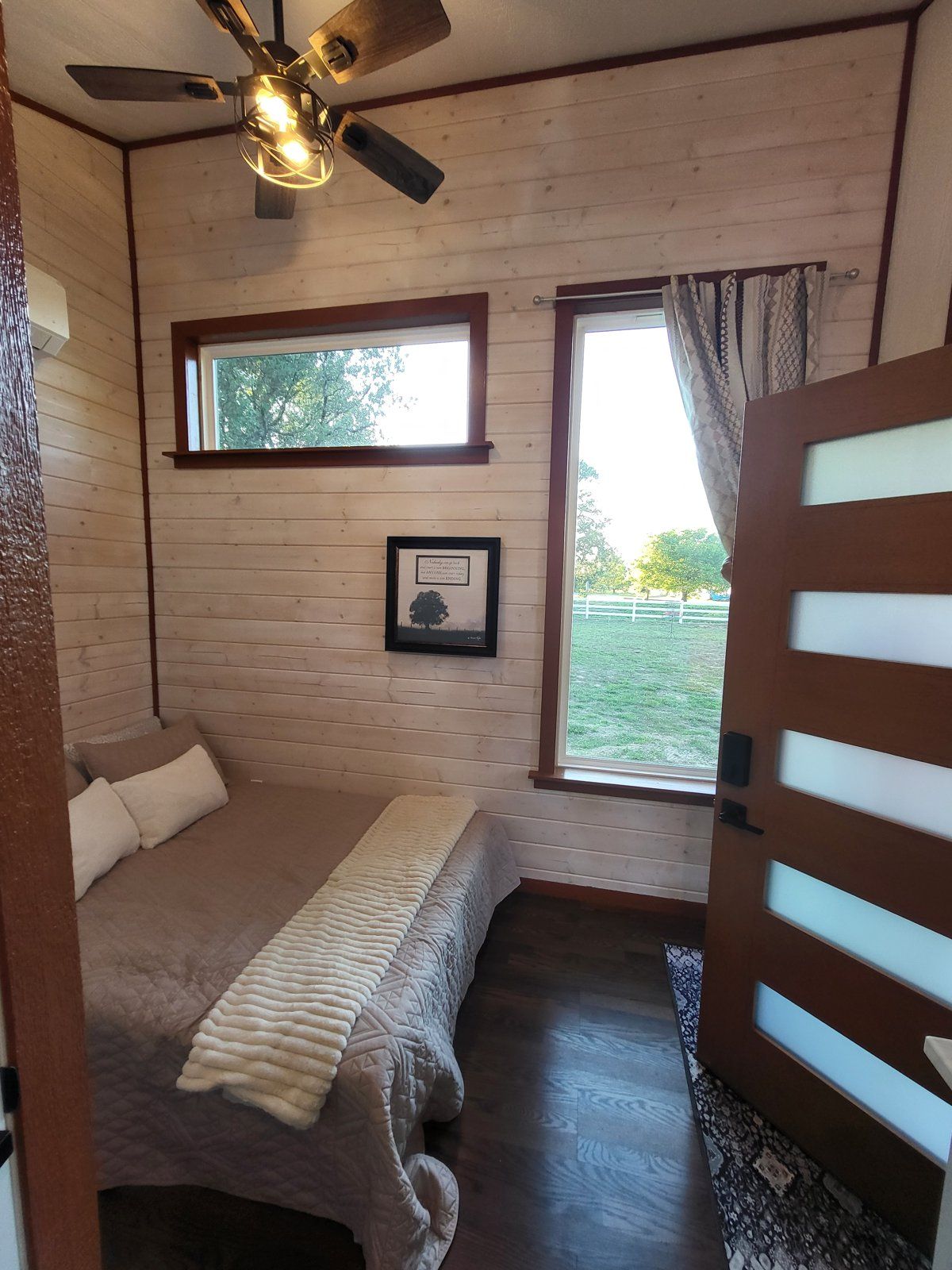 A bedroom with a bed, a ceiling fan, a window, and a door.