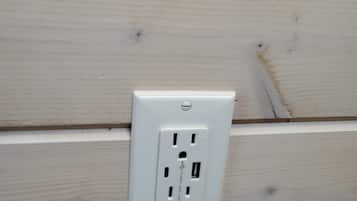 A white electrical outlet on a light-colored wooden wall.