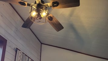 Une pièce dotée d’un ventilateur de plafond en bois, d’une fenêtre offrant une vue, d’une porte avec une fenêtre et d’un téléviseur fixé au mur.