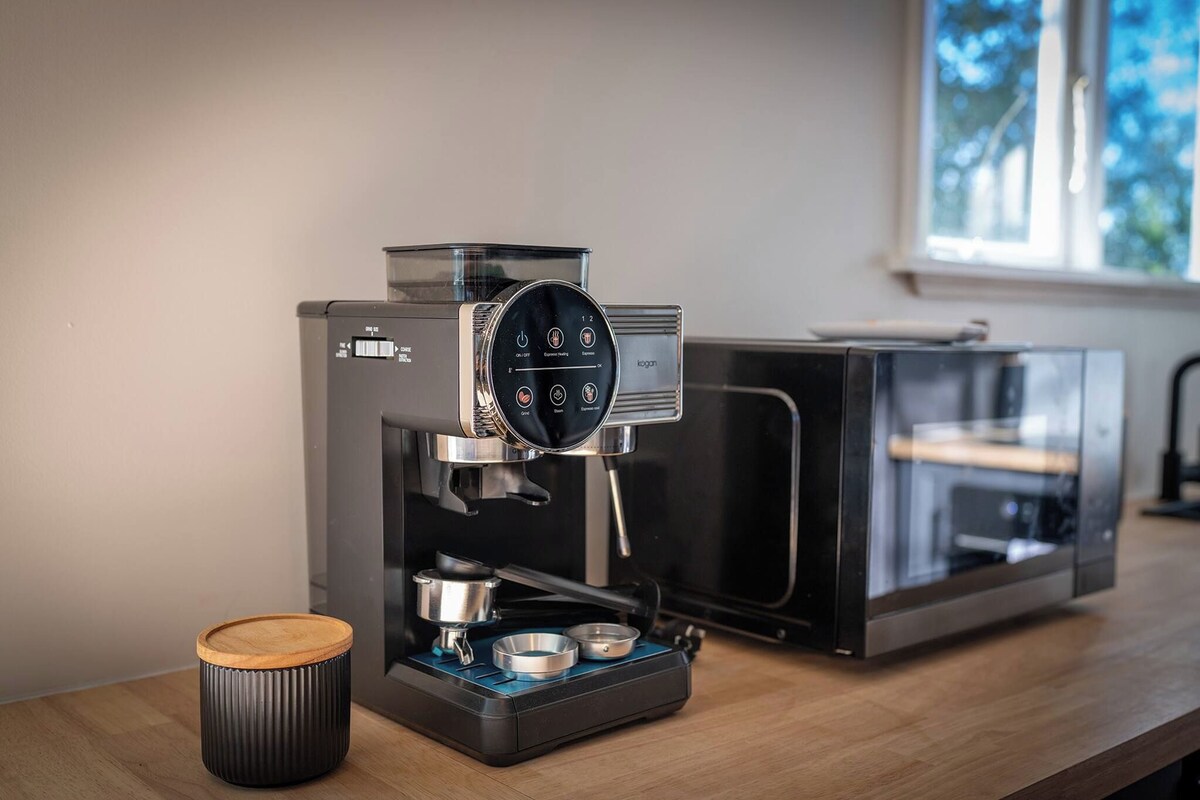 A modern coffee machine with a digital interface, a coffee grinder, and a water reservoir on a wooden countertop.