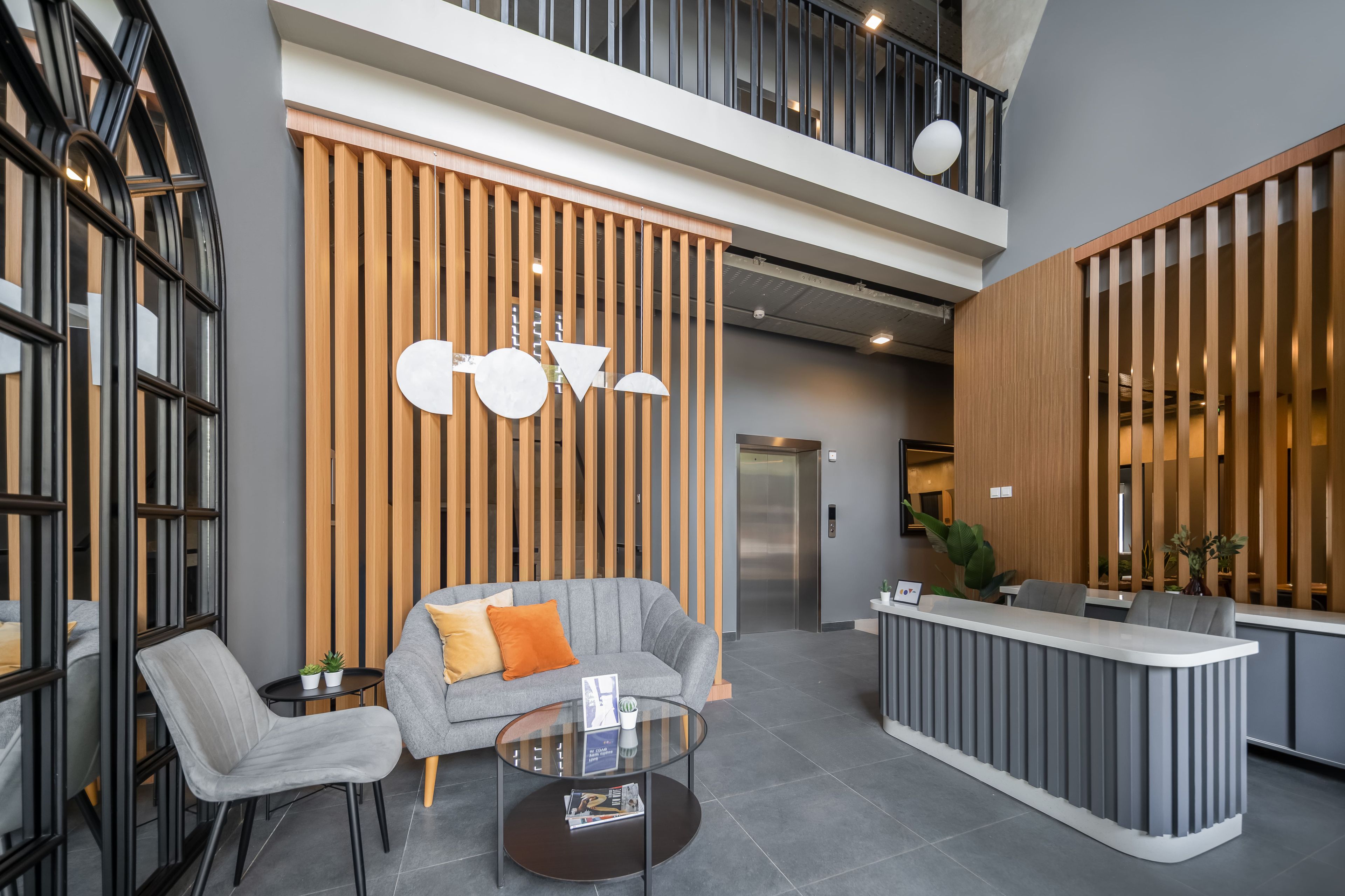 Un vestíbulo moderno con mostrador de recepción, zona de estar y escalera.