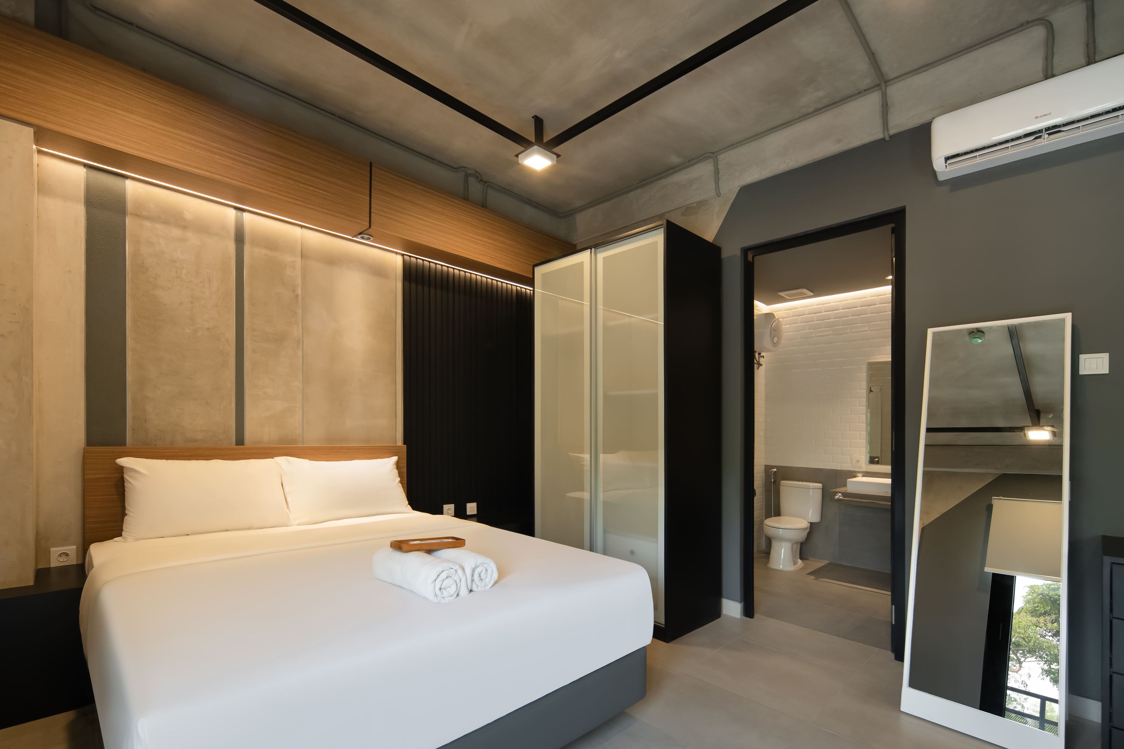 Ein modernes Hotelzimmer mit einem großen Bett, einem begehbaren Kleiderschrank, einem Badezimmer und Blick ins Freie.