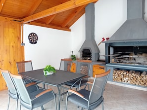 An outdoor dining area with a table and chairs, a dartboard, and a wood-fired oven. - Modern Holiday Home in Slavonia with Heated Pool, Spa and Private Pond (Nova Kapela)